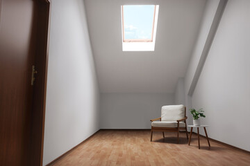 Fototapeta na wymiar Attic spacious room interior with slanted ceiling and furniture