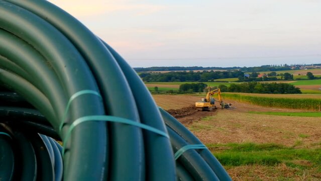 Water pipes and yellow excavator in the field. Carrying out water construction work.Plumbing installation.Pipe laying.Bringing water to the house. 4k footage