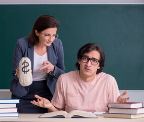 Old female teacher and male student in the classroom