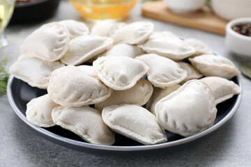 Raw dumplings (varenyky) and ingredients on grey table, closeup