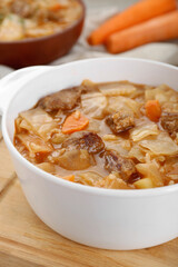 Tasty cabbage soup with meat and carrot on wooden board, closeup