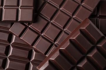 Many delicious dark chocolate bars as background, top view