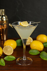 Lemon Martini cocktail, shaker and fresh fruits on wooden table