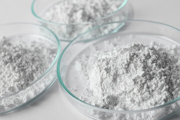 Petri dishes with calcium carbonate powder on white table, closeup