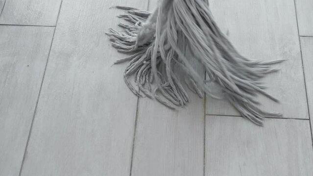 Unrecognizable person cleaning floor with rope mop. Closeup