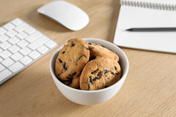 Chocolate chip cookies on wooden table at workplace