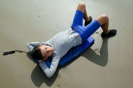 Young preteen boy laying on boogey board outside on the beach