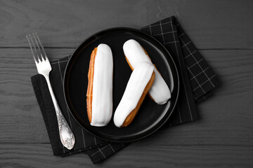 Delicious eclairs covered with glaze on grey wooden table, top view