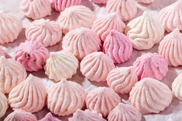 Pink meringue cookies with berry flavor on baking parchment