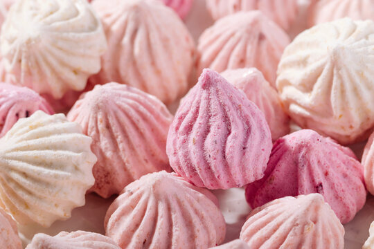 Pink meringue cookies with berry flavor on baking parchment