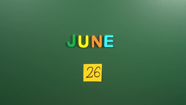 Hand sticking a sticker 26 June calendar day on school board. 26 date of June. Twenty sixth day of June. 26th date number. 26 day calendar. Twenty six date. Against Drug Abuse