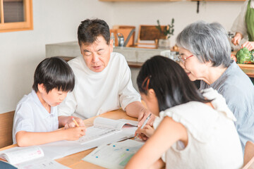 Fototapeta premium 家のダイニングで孫の宿題を教える高齢者夫婦と小学生の子供 