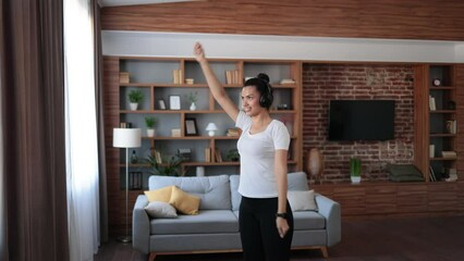 Focused african woman in sport clothes doing fitness exercises with hands during workout at home. Active young brunette enjoying morning training for staying fit and healthy.