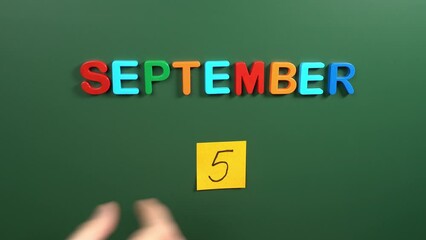 Hand sticking a sticker 5 September calendar day on school board. 5 date of September. Fifth day of September. 5th date number. 5 day calendar. Five date. International Day of Charity, india Teachers