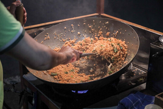 A man cooking fried rice on steel skillet pan for selling on the street food. Indonesian call the dish Nasi Goreng. Indonesian Street food culinary
