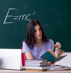 Young female teacher student in front of green board