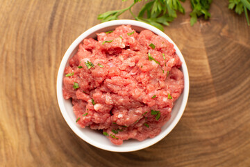Raw Ground Beef in White Bowl on Wooden Board from Above