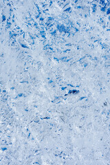 Fototapeta na wymiar Abstract ice background. Blue background with cracks on the ice surface. Transparent ice crystals texture the cracked background. Selective focus.