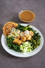 pecal or Indonesian salad is a boiled vegetables topping with tofu, tempeh, peanut sauce and crackers
