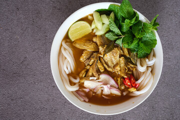 asam laksa, laksa medan is rice noodle, fish with sour soup and a little sweet and spicy. topping cucumber, onion, chili and mint leaves