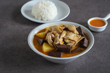 chicken curry or kari ayam made from coconut milk, spices, potato and chicken blood . usually eaten with cooked rice or vermicelli rice