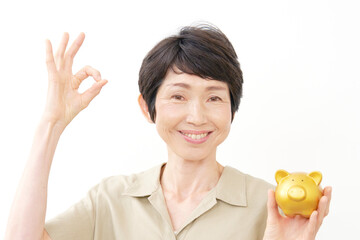 貯金箱を持ってOKサインする中年女性　白背景
