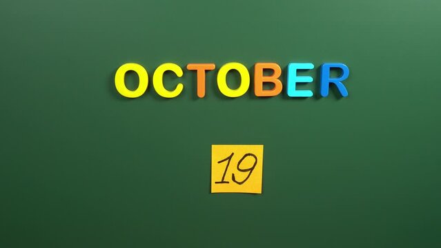 Hand sticking a sticker 19 October calendar day on school board. 19 date of October. Nineteenth day of October. 19th date number. 19 day calendar. Nineteen date. breast cancer, Ataturk, Kentucky