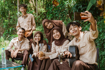 group of youth scouts taking selfies together using a cellphone camera while camping