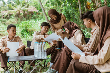 Scout youth members work together on paper assignments when they gather in nature