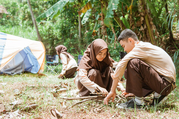 Asian boy scouts and girl scouts collecting firewood in nature