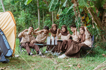 Fototapeta na wymiar group of young scouts smiling at the camera with united hand gestures when gathering in nature
