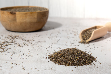 Heap of Chia seeds with wooden spoon. Healthy superfood rich in Omega 3 fatty acids. Dry healthy natural ingredient. Chia grains are falling. Vegetarian food 