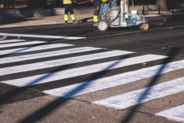 Process of making new road surface markings with a line striping machine, workers improve city infrastructure, demarcation marking of pedestrian crossing with a hot melted paint on asphalt pavement