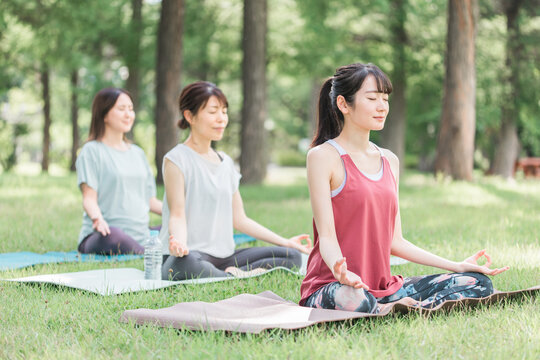 健康・ダイエットのため公園でヨガ教室・ヨガ・ピラティスをする女性達
