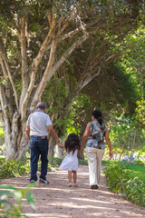 Fototapeta premium Family people walking holding hands in a park during daytime