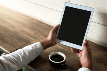 Mockup image of a man holding digital tablet with blank white screen with coffee cup in cafe