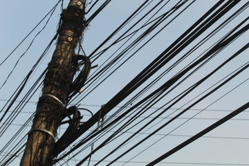 Electric poles and wires against a blue sky make for a striking image. The towering poles and intricate web of wires are a testament to modern technology, providing electricity to homes and businesses