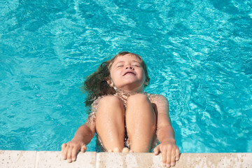 Child in summer swimming pool. Happy little kid boy playing with in outdoor swimming pool on hot summer day. Kids learn to swim. Family beach vacation.