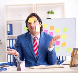 Young male handsome employee in conflicting priorities concept