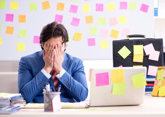 Young male handsome employee in conflicting priorities concept