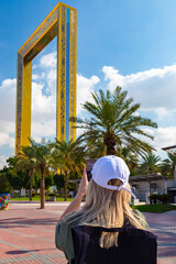 emale tourist in white cap photographs the landmark of the city frame of Dubai.