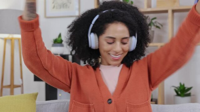 Woman, dance and music with headphones on a living room sofa with happiness at home. Web radio, online and listening of a happy and relax female in a house on a lounge couch dancing with audio