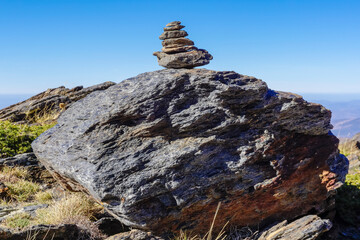 Flat gray stones piled up forming a pyramid and marking the path of a path in the mountains