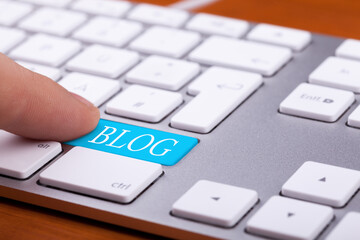 Finger pressing on blog button on keyboard. Online writing and succes