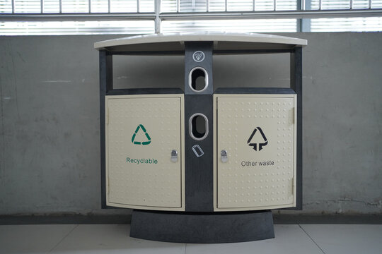 Bin for recyclables and other waste in front of the row of plants