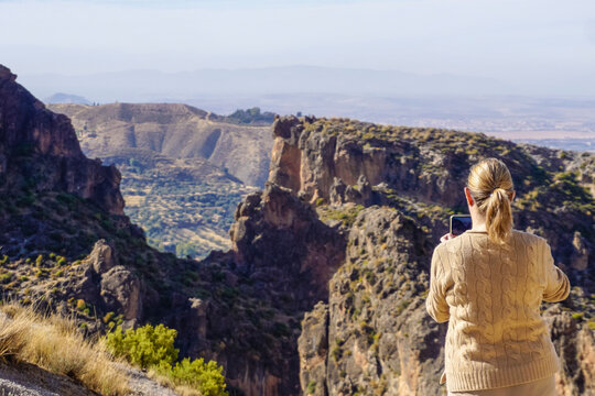 Beautiful young and blonde woman taking photos in a canyon of the Alpujarras region of Granada