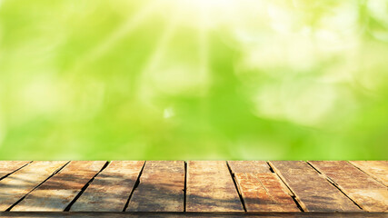 Wooden table top with natural green blurred background or various leaves, fresh bright sunlight, product empty concept.