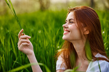 portrait of a happy, laughing woman sitting in tall grass in a field