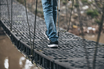 Hikers use trekking pole with backpacks and hold map walking through the bridge in the forest. hiking and adventure concept.