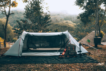 Gray tent on the grass in the forest The view behind is the mountain in the morning. Camping,...
